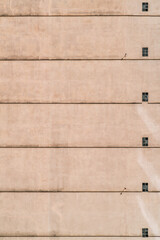 A vertical shot of a residential building wall with a sequence of small windows and floor separation lines on the plastered facade; a seamless texture of a house elevation with windows and stripes