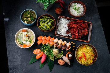 Asian food table with various kind of chinese food, noodles, sour soup, rice, sushi
