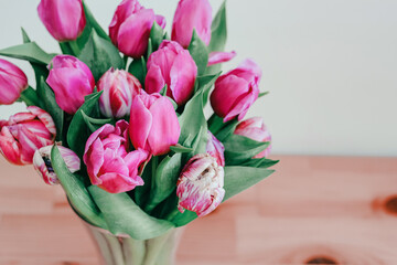 Close up tulips bouquet in a vase over wooden background 8 March greeting