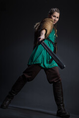 A female Viking warrior in a fur cape attacks with a sword. portrait on a black background