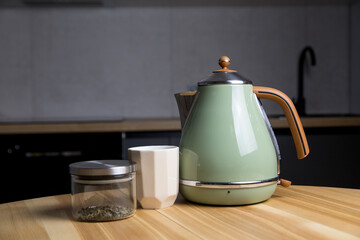 stylish teapot, cup and green tea stand on a wooden table in the kitchen