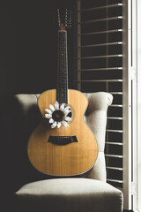 Acoustic guitar on chair with white flower.