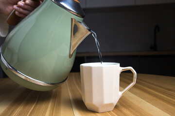 pouring hot water from an electric kettle into a tea cup