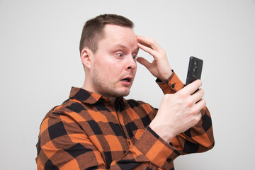 Man being shocked while looking at his smartphone