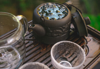 Chinese outdoor tea ceremony with a clay teapot and cups on a blurry background.	
