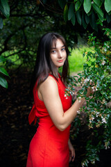 Young woman in red dress posing in a forest