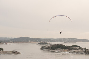 Paraglider gliding over an icy fjord.