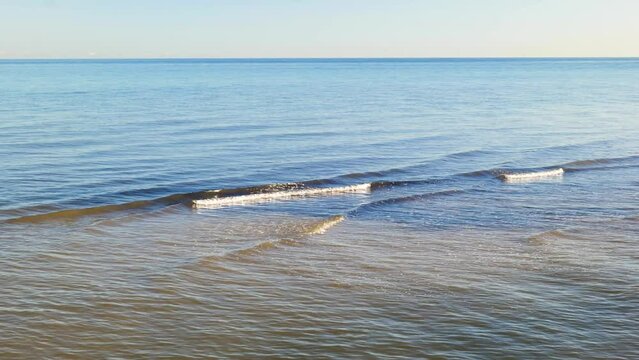 Small Waves Roll into Coast under Ocean Horizon