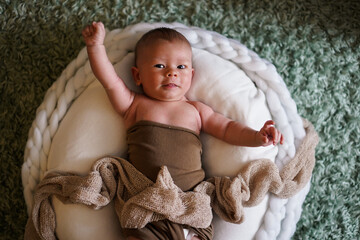 happy cheering naked newborn baby lying on a white round bed with arms up and fists looking into the camera as a winner shouting yay hooray - obrazy, fototapety, plakaty