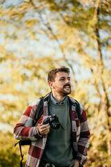 
Portrait of thoughtful backpacker taking pictures outdoors. Inspired photographer film natural view
