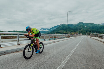 Fototapeta premium Full length portrait of an active triathlete in sportswear and with a protective helmet riding a bicycle. Selective focus 