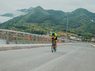 Full length portrait of an active triathlete in sportswear and with a protective helmet riding a...
