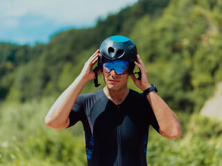 Close up photo of an active triathlete in sportswear and with a protective helmet riding a bicycle....