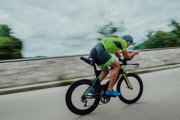 Full length portrait of an active triathlete in sportswear and with a protective helmet riding a...