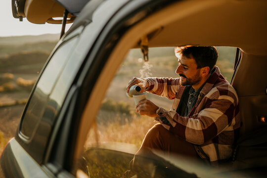 A Man Has Arrived For A Camping Trip, So He Takes A Coffee Break While Sitting In The Trunk Of The Car