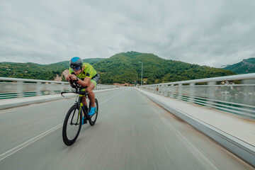 Full length portrait of an active triathlete in sportswear and with a protective helmet riding a...