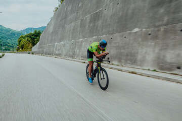 Full length portrait of an active triathlete in sportswear and with a protective helmet riding a...