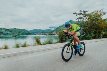 Full length portrait of an active triathlete in sportswear and with a protective helmet riding a...