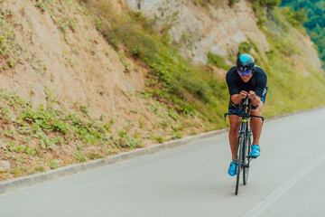 Obraz premium Full length portrait of an active triathlete in sportswear and with a protective helmet riding a bicycle. Selective focus 