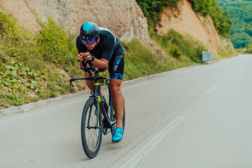 Full length portrait of an active triathlete in sportswear and with a protective helmet riding a...