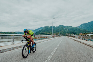 Full length portrait of an active triathlete in sportswear and with a protective helmet riding a bicycle. Selective focus 
