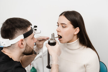 Cryo procedures for mucosal renewal and treatment of chronic pharyngitis and tonsillitis. Male doctor otolaryngologist with cryosprayer. ENT doctor is preparing for nitrogen cryotherapy.