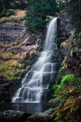 Beautiful waterfall in the wilderness area cascading down the black rock cliff - 565484865