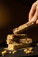 Woman takes Homemade natural Granola energy bar. Variety of Protein granola breakfast bars, with nuts, raisins dried cherries and chocolate. Healthy nutrition eating. Gluten free cereal dieting snack