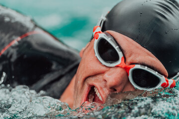 A triathlete in a professional swimming suit trains on the river while preparing for Olympic...