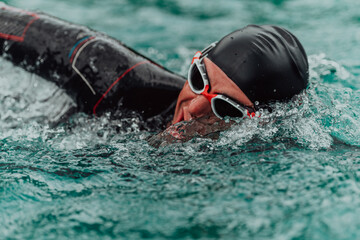 A triathlete in a professional swimming suit trains on the river while preparing for Olympic...