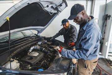 Skilled mechanics inspecting a car engine using tools in a modern auto repair shop. High-quality photo
