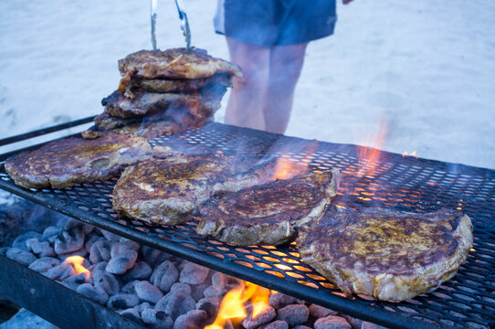 Cooking steaks on a fire.