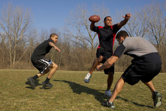 A quarterback is getting a pass off before he is sacked during a game of touch football.