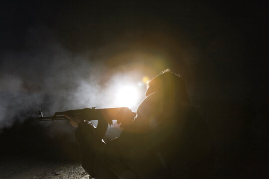 Man shooting a rifle at night with light