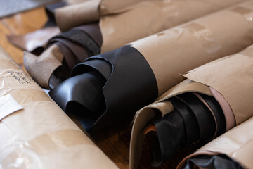 Rolls of black natural full grain leather wrapped in paper. Raw textured leather materials for manufacture of bags, shoes, clothing and accessories. © Benjamin Asher