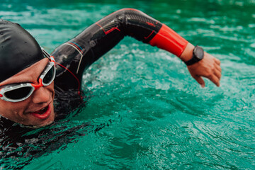 A triathlete in a professional swimming suit trains on the river while preparing for Olympic...