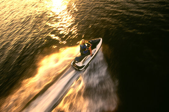 Aerial View a woman racing across the lake on her jet ski.
