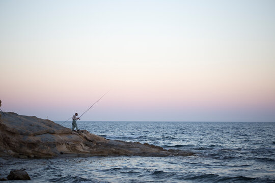 A man fishing in Calpe at sunset