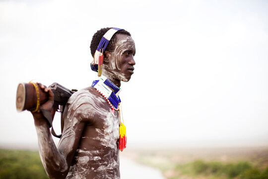 A young man holds his kalashnikov rifle while overlooking the Omo river in the remote Omo Valley of Ethiopia