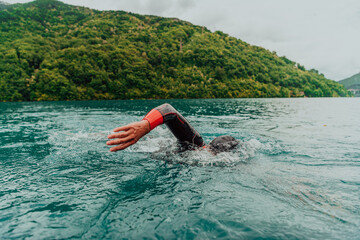 A triathlete in a professional swimming suit trains on the river while preparing for Olympic...