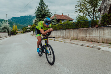 Full length portrait of an active triathlete in sportswear and with a protective helmet riding a...