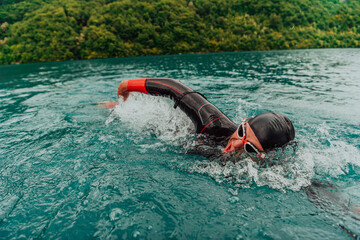 A triathlete in a professional swimming suit trains on the river while preparing for Olympic...