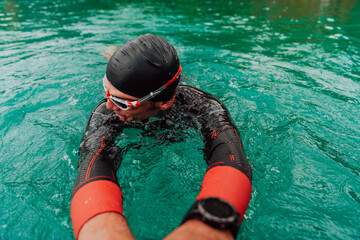 A triathlete in a professional swimming suit trains on the river while preparing for Olympic...