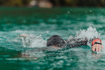 A triathlete in a professional swimming suit trains on the river while preparing for Olympic...