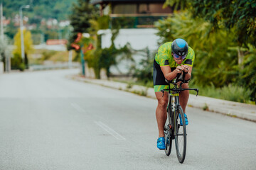 Full length portrait of an active triathlete in sportswear and with a protective helmet riding a...