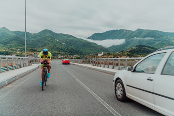 Full length portrait of an active triathlete in sportswear and with a protective helmet riding a...