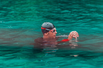 A triathlete in a professional swimming suit trains on the river while preparing for Olympic swimming