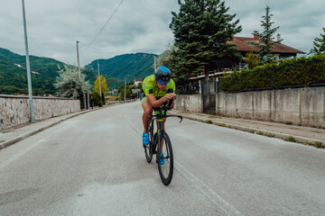 Full length portrait of an active triathlete in sportswear and with a protective helmet riding a...