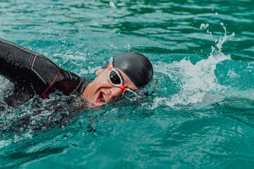A triathlete in a professional swimming suit trains on the river while preparing for Olympic...