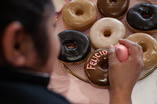 Repostera adornando con letras de colores las donas y rosquillas